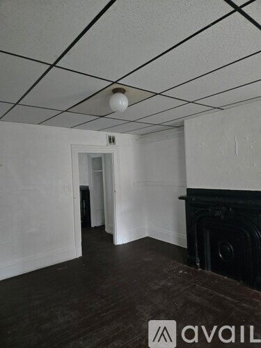 A room with a fireplace and a doorway leading to another room.