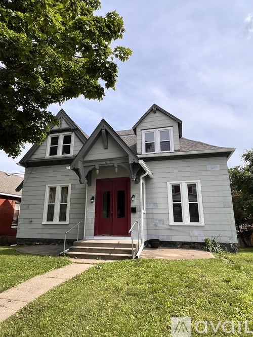 A house with a red door and a tree in front.