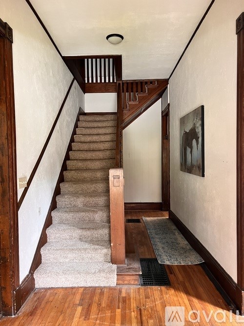 A staircase with a carpeted runner and a wooden handrail.