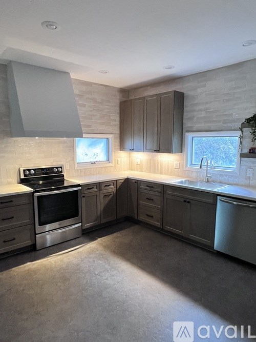 A modern kitchen with a stove, sink, and cabinets.