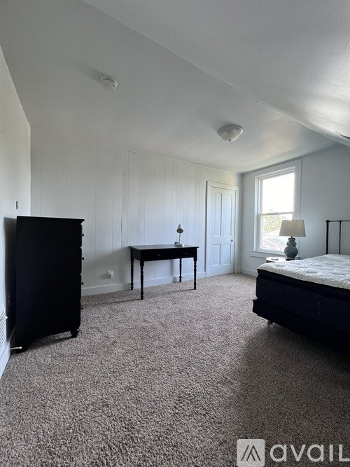 A bedroom with a bed, desk, and chair.