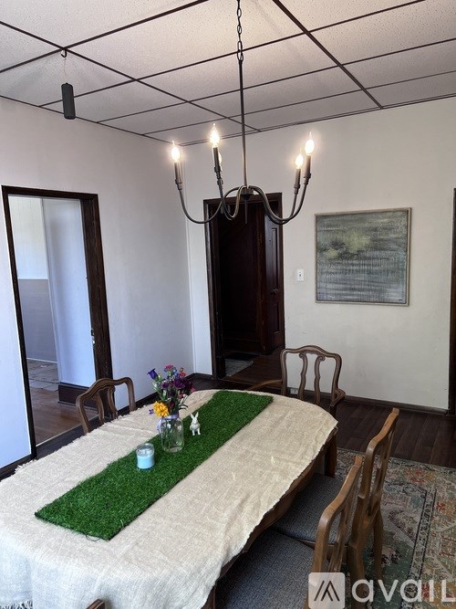 A dining room with a table set for two and a chandelier hanging from the ceiling.
