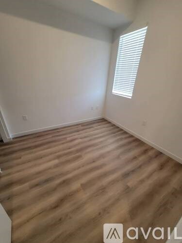 A room with wooden flooring and a window with blinds.