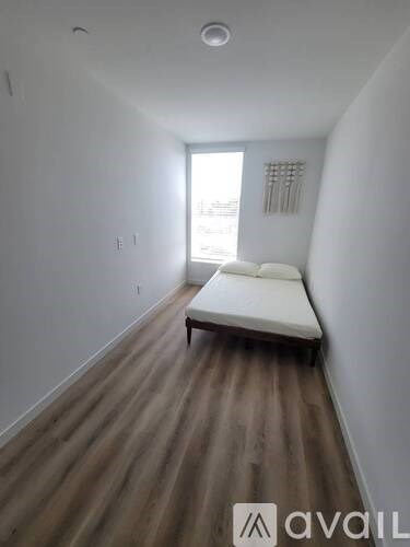 A room with a bed and wooden floors.