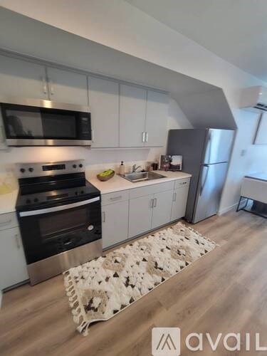 A kitchen with a stove top oven, microwave, refrigerator, and cabinets.