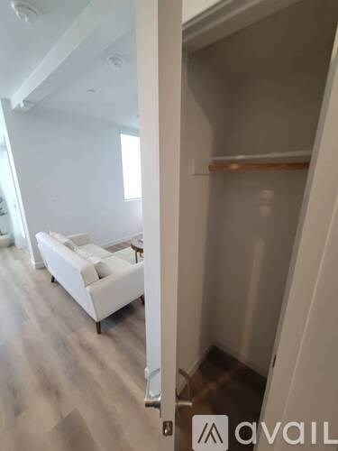 A white couch is in a room with a white wall and a wooden floor.