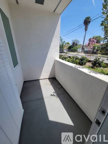 A balcony with a view of a street and palm trees.
