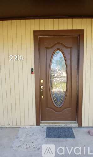 A brown door with a glass window and a doormat in front of it.