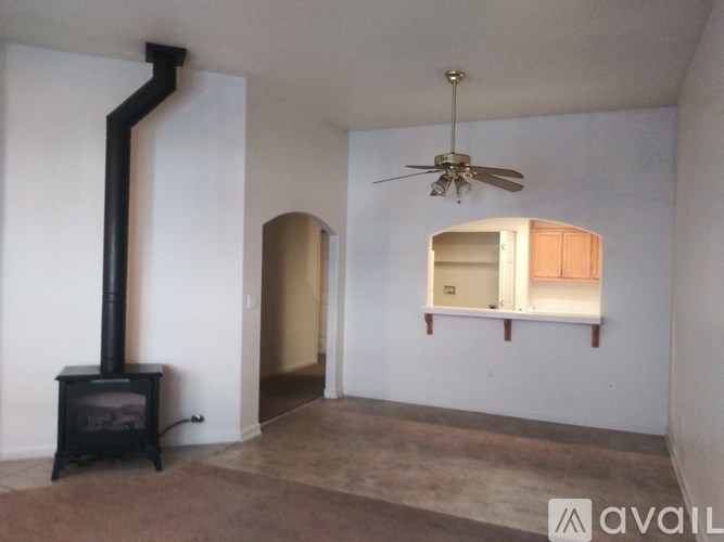 A room with a wood stove and a ceiling fan.