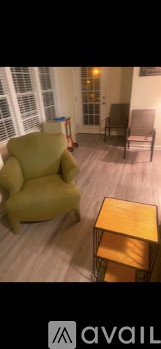 A yellow chair is in a room with a wooden table and a grey sofa.