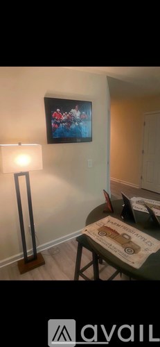 A lamp stands next to a painting on a wall.