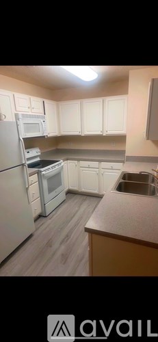 A kitchen with white cabinets and a refrigerator.