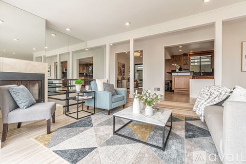 A modern living room with a grey sofa, a black coffee table, and a rug with a geometric pattern.