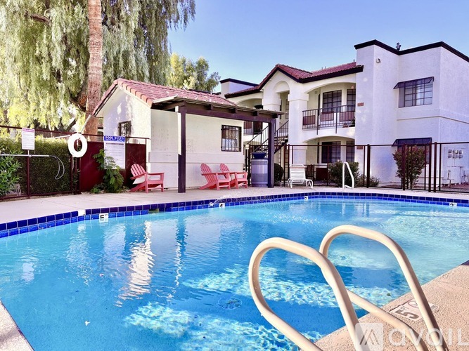 A pool in front of a house with a red and white striped fence.