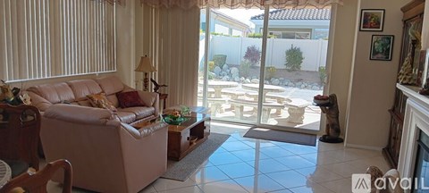 A living room with a couch, chair, and a table with a vase of flowers on it.