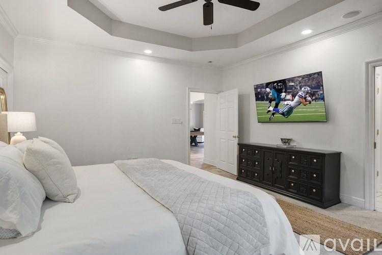 A bedroom with a large bed and a TV mounted on the wall.