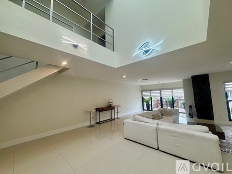 A modern living room with a white sofa and a staircase.