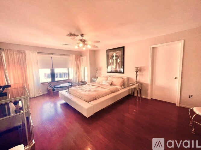 A bedroom with a large bed and a ceiling fan.