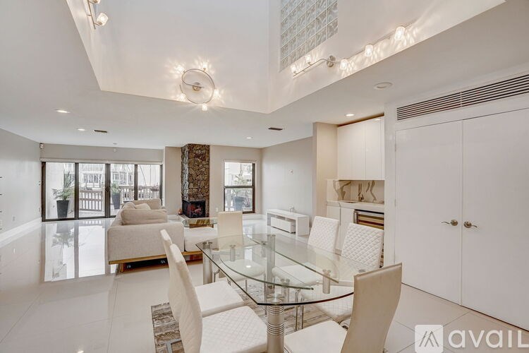 A modern dining room with a glass table and white chairs.