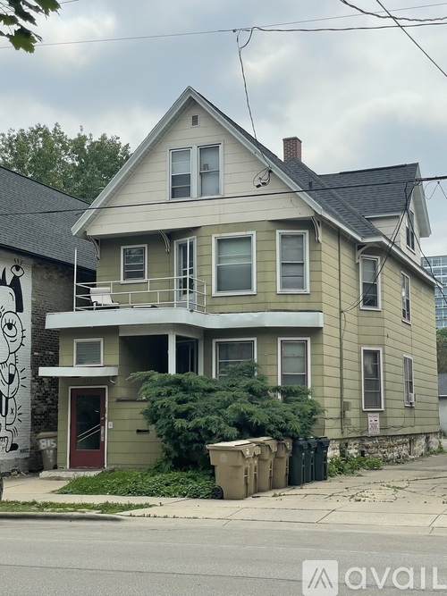 A two-story house with a red door and a balcony on the second floor.
