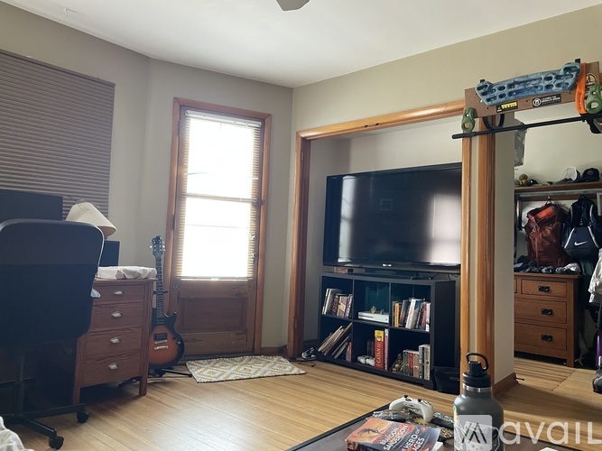 A living room with a guitar, a TV, a bookshelf, and a window.
