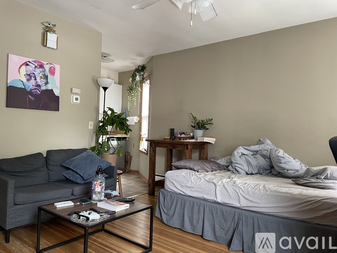 A living room with a grey couch, a grey bed, and a painting on the wall.