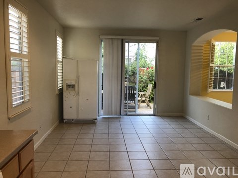 A kitchen area with a refrigerator, sink, and a window with blinds.