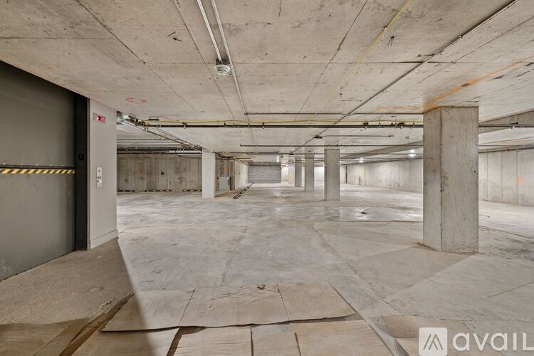 A large, empty parking garage with concrete pillars and a grey floor.