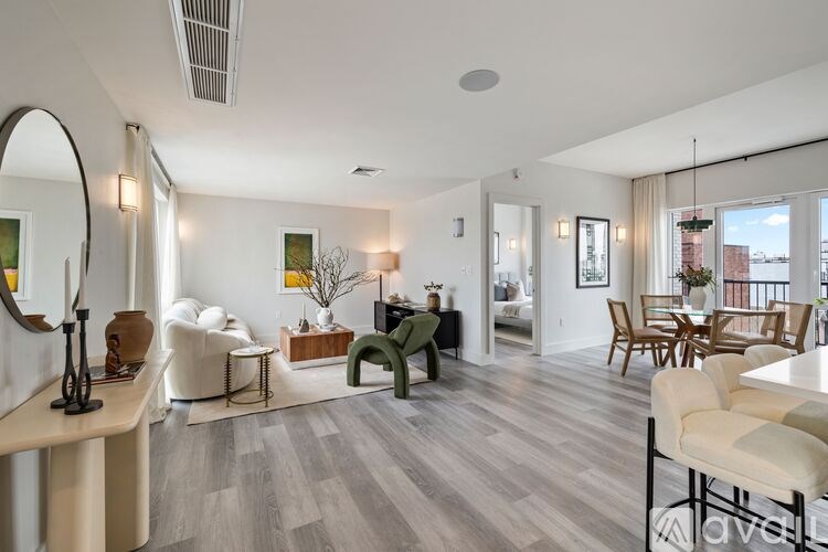 A living room with a white couch, a green chair, and a wooden table.