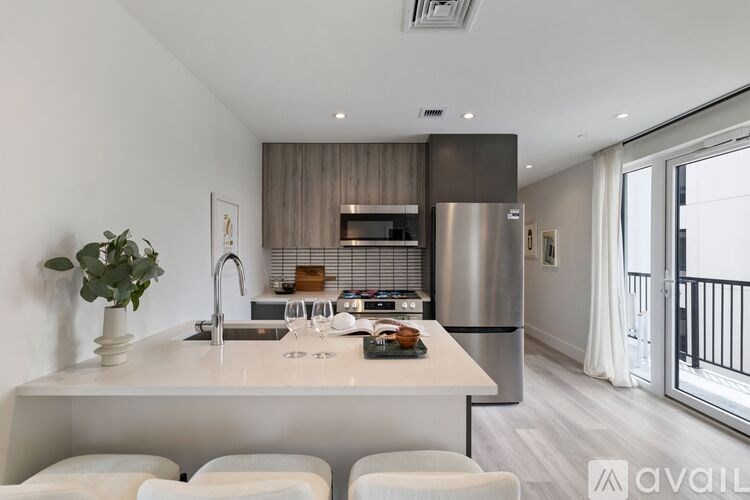A modern kitchen with a large island and white chairs.