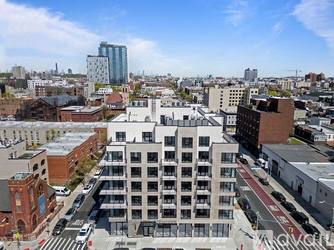 A cityscape with a mix of modern and older buildings, a clear sky, and a road with vehicles.
