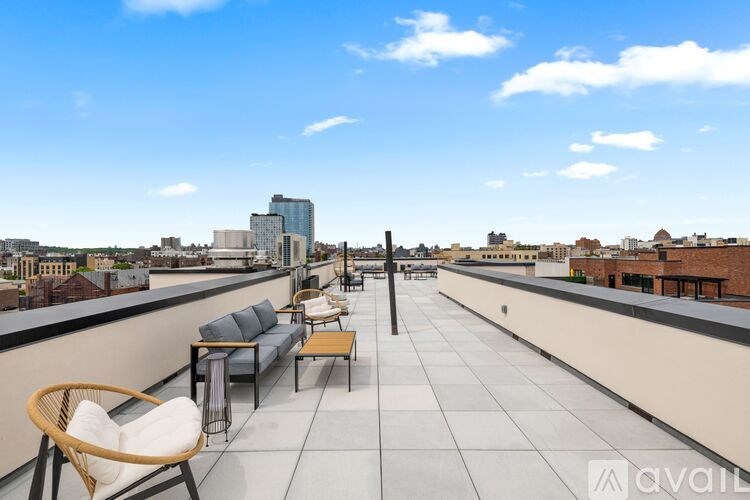 A rooftop patio with a white chair and a black table.