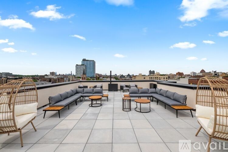 A rooftop patio with wicker chairs and tables overlooking a city skyline.