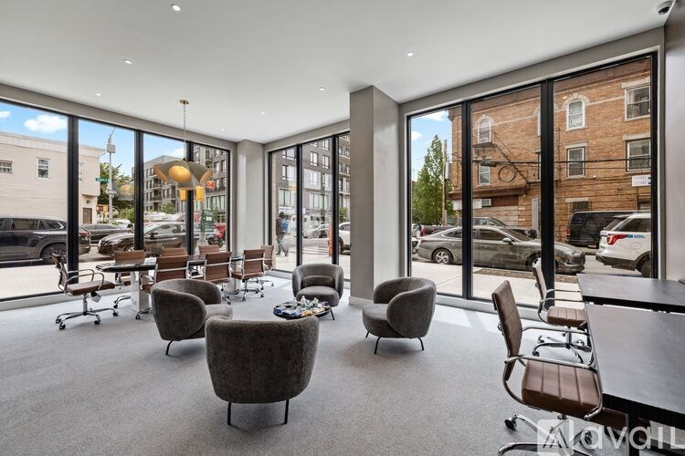 A spacious waiting room with grey chairs and a view of the street outside.