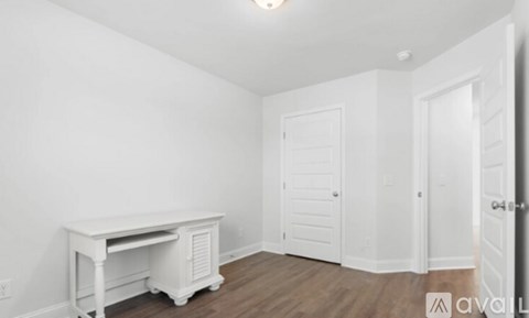 A white desk sits in a room with wood floors and white walls.