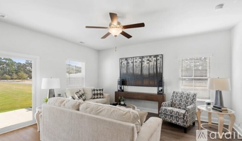 A living room with a white couch, a chair, and a ceiling fan.