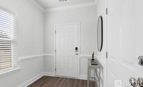 A white door is in a room with a mirror and a candle on a table.