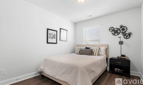 A bedroom with a bed, nightstand, and two picture frames on the wall.