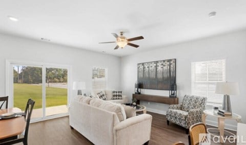 A living room with a couch, chairs, and a ceiling fan.