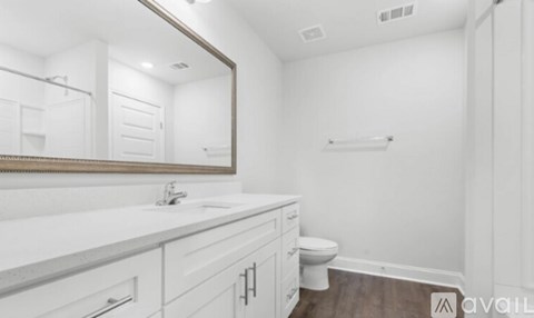 A white bathroom with a toilet, sink, and mirror.