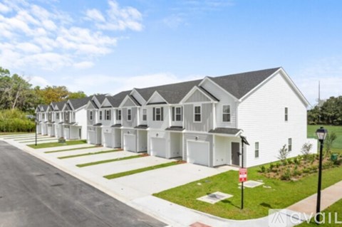 A row of white houses with a red sign in front of the first one.