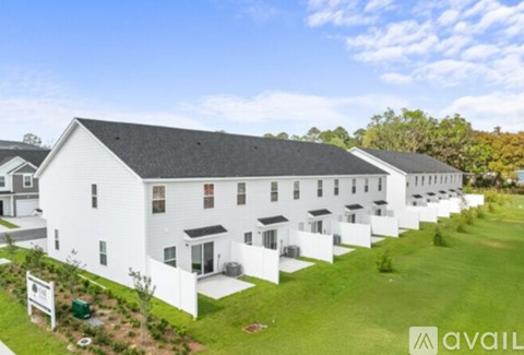 A white building with a black roof is surrounded by green grass.