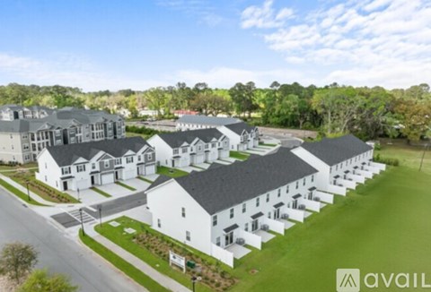 A row of white houses with a grassy area in front.