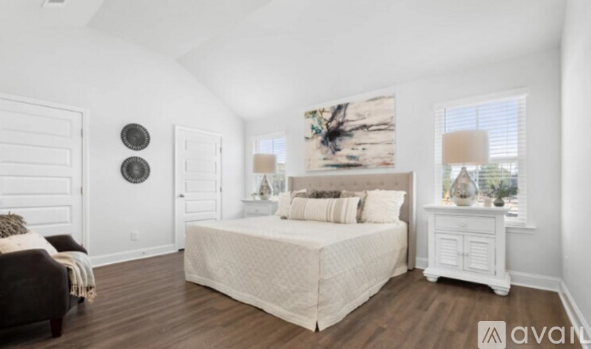 A bedroom with a large bed and a wooden floor.