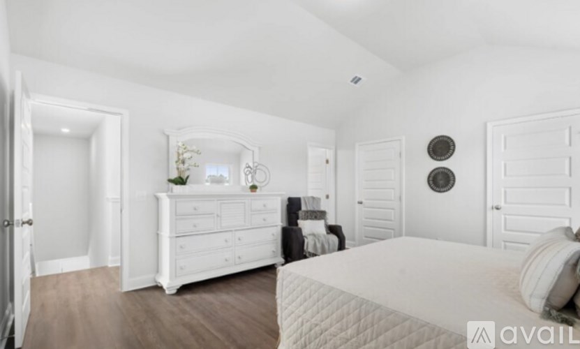 A white bedroom with a large bed and a dresser.
