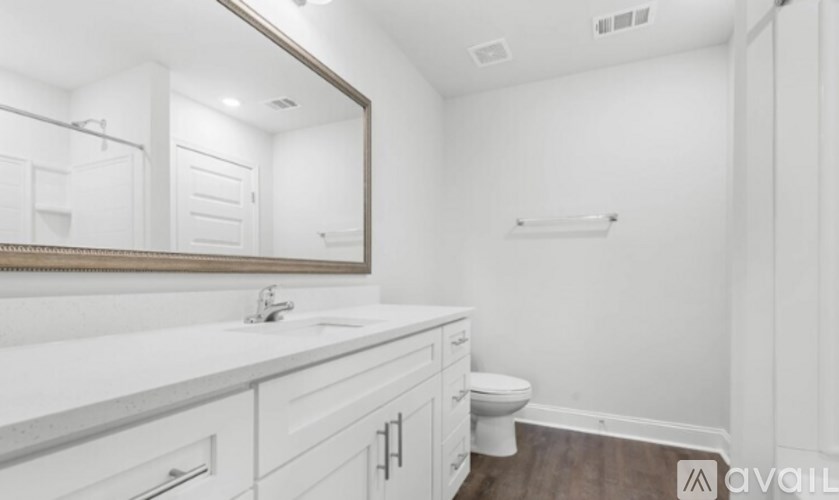 A white bathroom with a toilet, sink, and mirror.