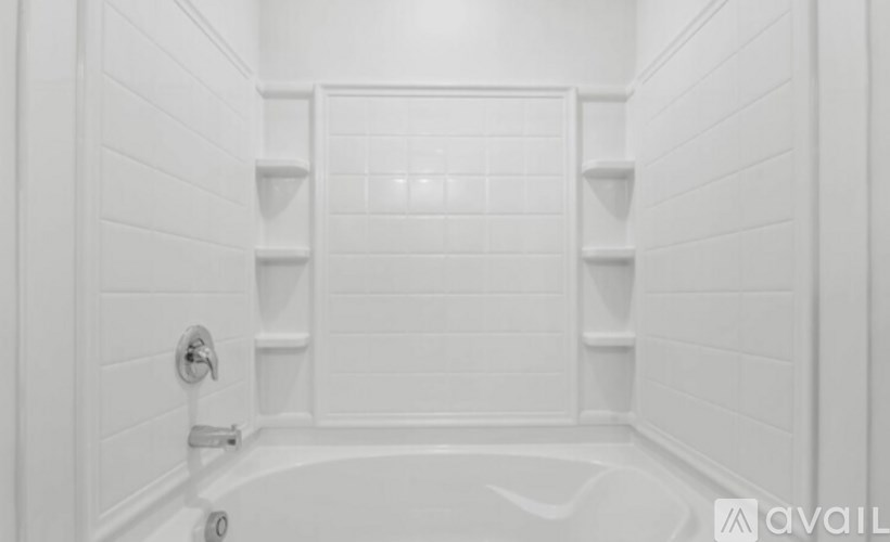 A white bathroom with a tub and shelves.