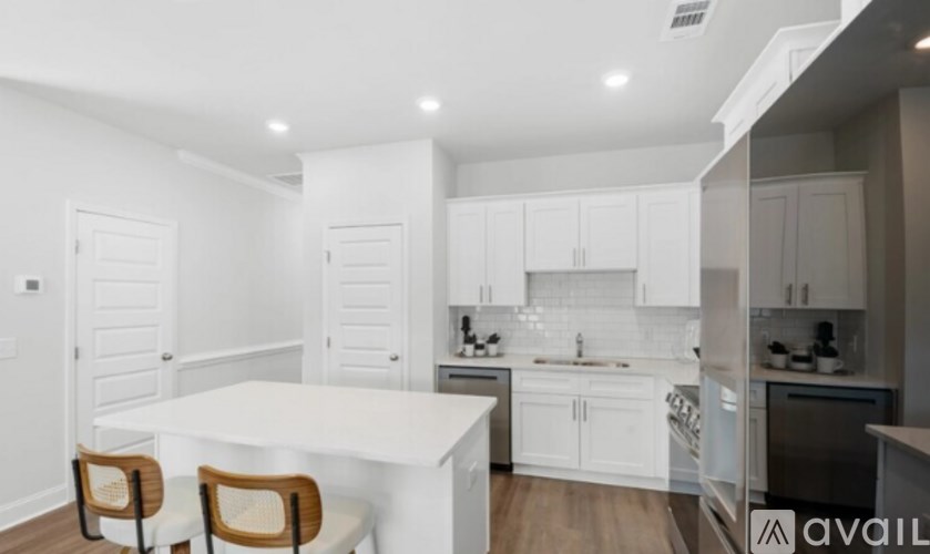A modern kitchen with white cabinets and a dining table.