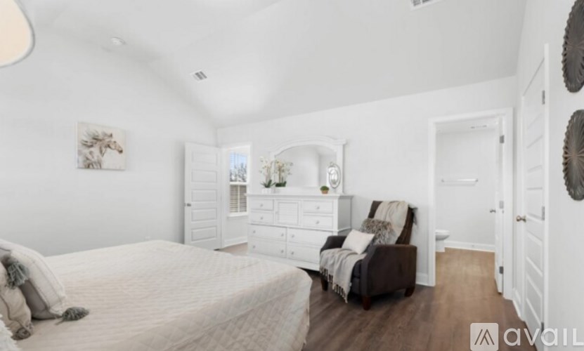 A bedroom with a large bed and a chair.