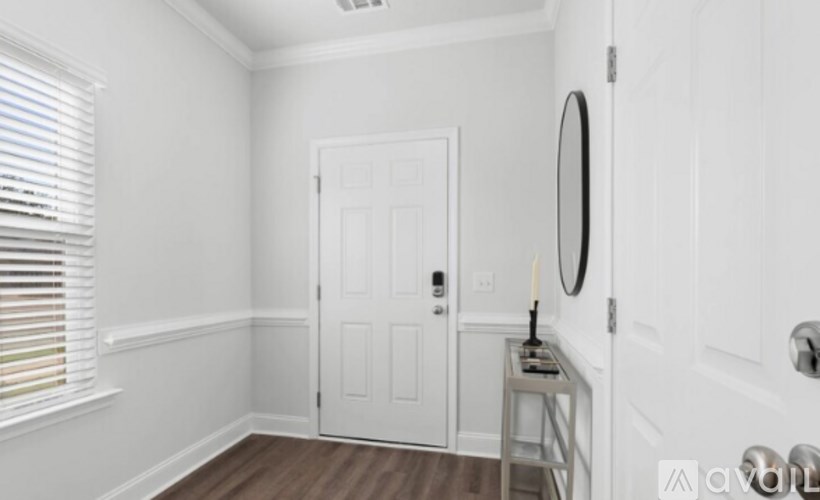 A white door is in a room with a mirror and a candle on a table.